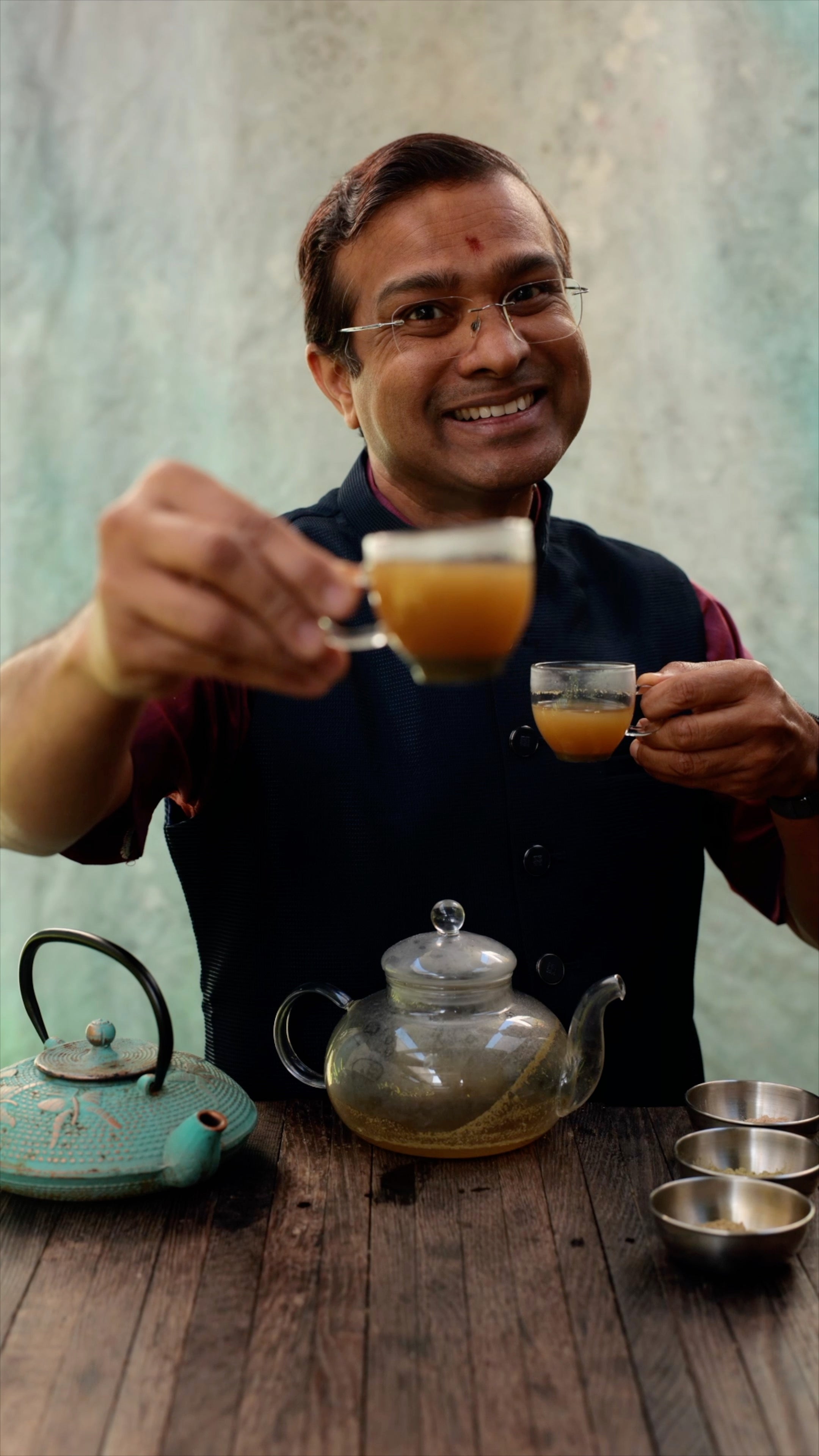 Vaidya Jay smiling, offering two cups of the liver tea elixir