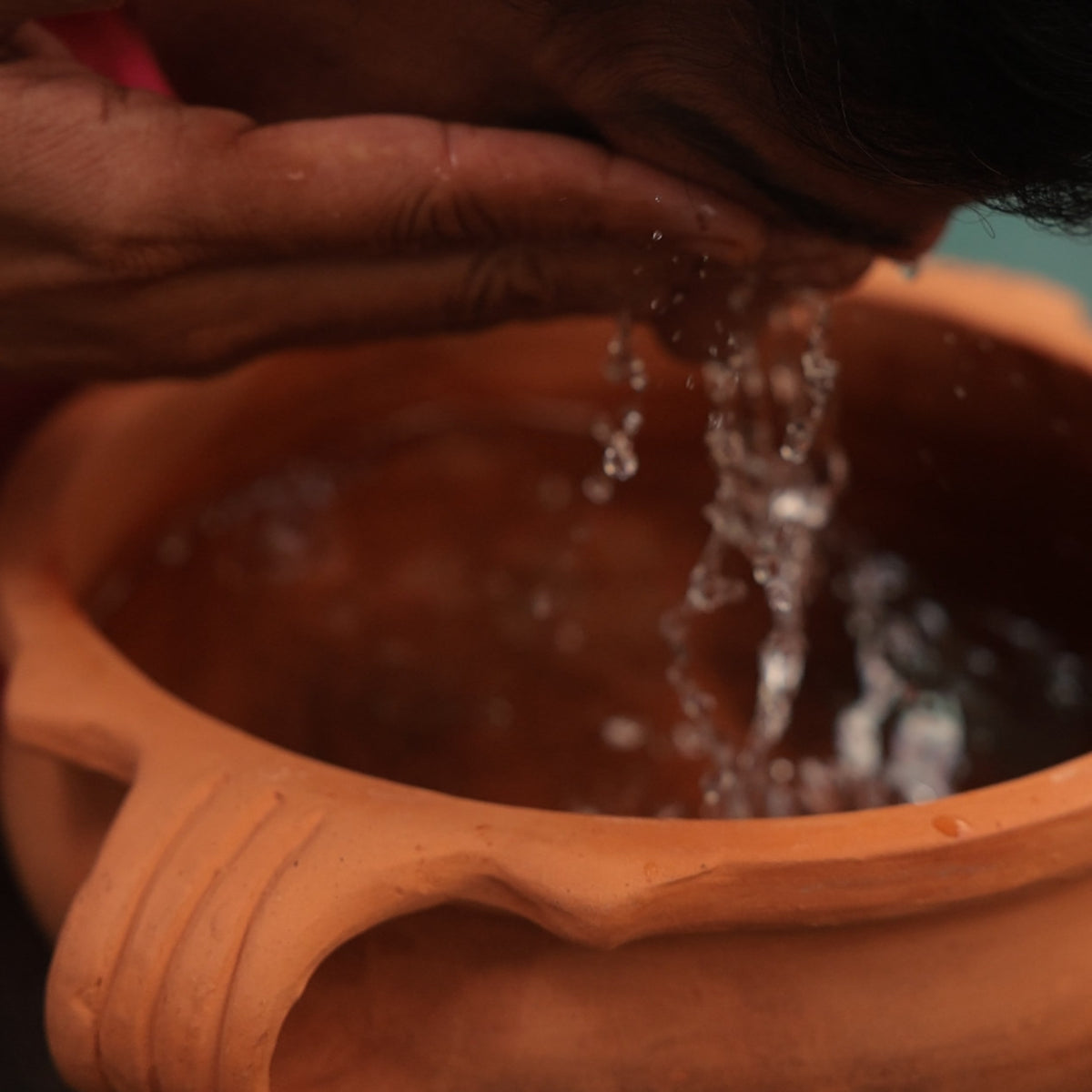 Vaidya Jay splashing cold water into his eyes over a clay bowl