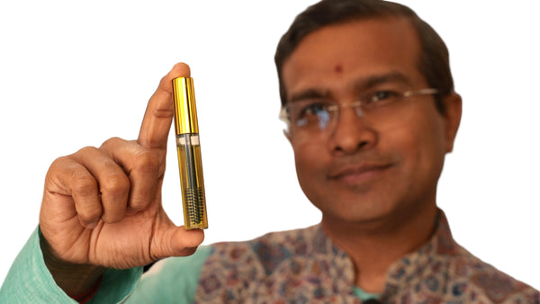 Man holding a gold and black cylindrical object against a plain background