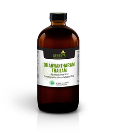 A dark glass bottle with a white label that reads 'Dhanwantharam Thailam' and indicates it is a warming herbal oil for joint support.
